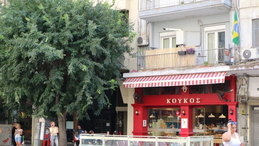Red storefront with greek writing and outdoor seating